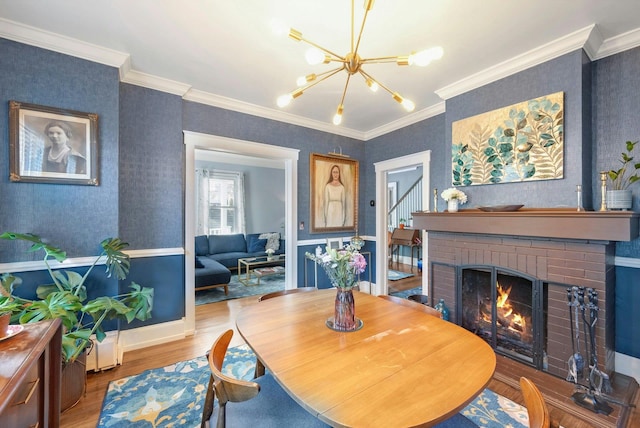 dining area with hardwood / wood-style flooring, a fireplace, a chandelier, and crown molding