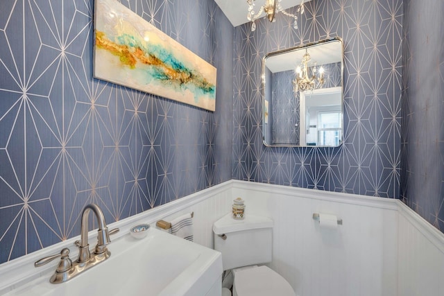 bathroom with sink, a notable chandelier, and toilet