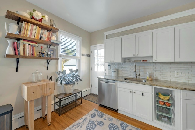 kitchen with sink, dishwasher, white cabinetry, light stone counters, and light wood-type flooring