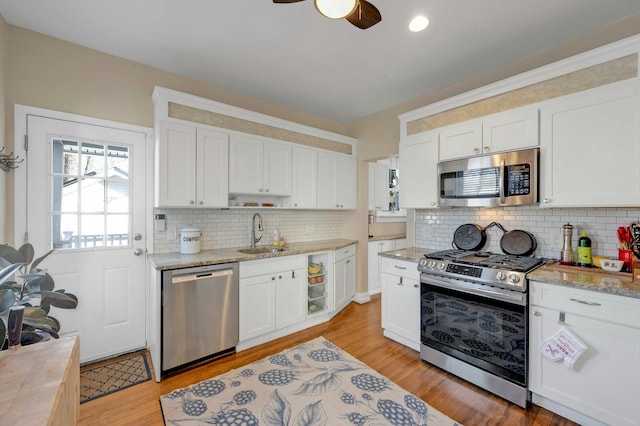 kitchen with white cabinetry, sink, light hardwood / wood-style floors, and appliances with stainless steel finishes