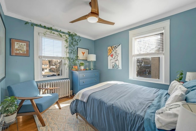 bedroom with ornamental molding, radiator, ceiling fan, and light wood-type flooring