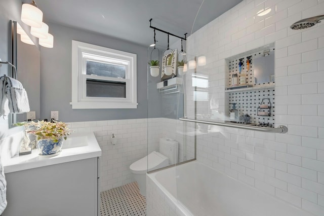 full bathroom with tile walls, tiled shower / bath combo, vanity, tile patterned flooring, and toilet