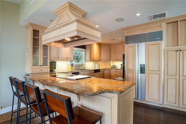 kitchen featuring a kitchen bar, decorative backsplash, paneled fridge, custom range hood, and dark wood-type flooring