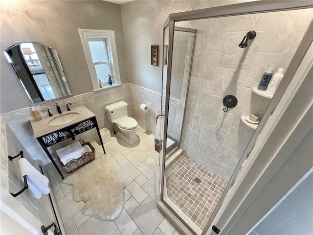 bathroom with vanity, toilet, tile walls, and a shower with shower door