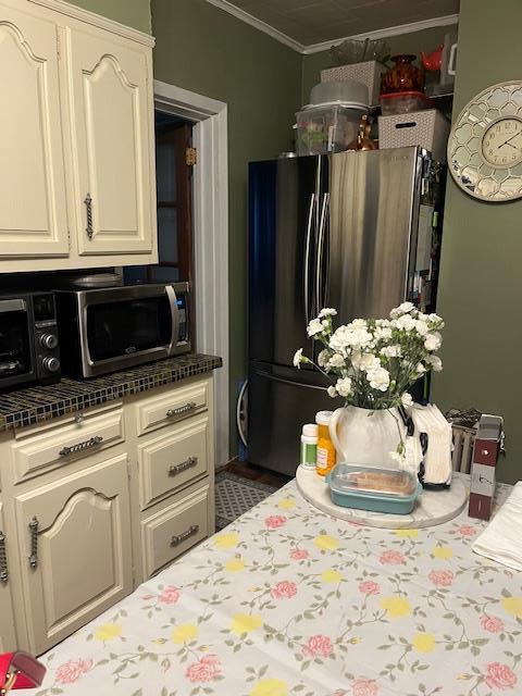 kitchen with ornamental molding, stainless steel appliances, and cream cabinets