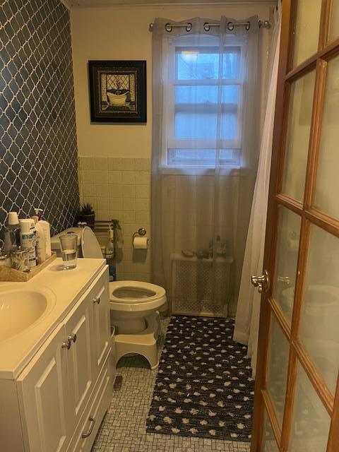 bathroom featuring vanity, toilet, and tile walls