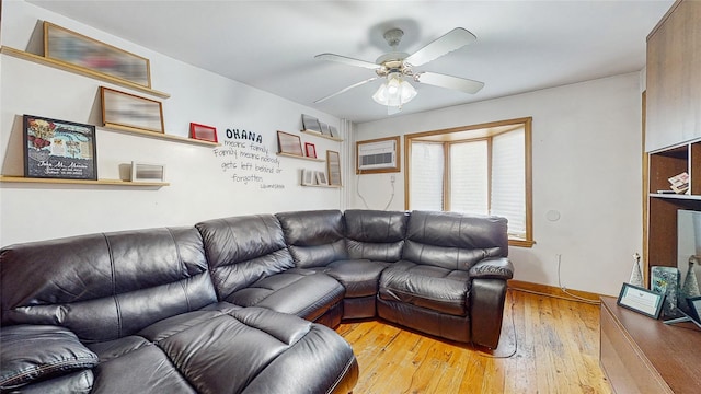 living room featuring a wall mounted air conditioner, light hardwood / wood-style floors, and ceiling fan