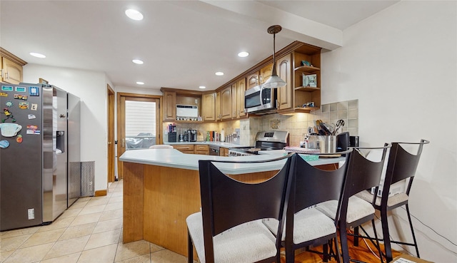 kitchen featuring stainless steel appliances, kitchen peninsula, a kitchen bar, decorative backsplash, and light tile patterned floors