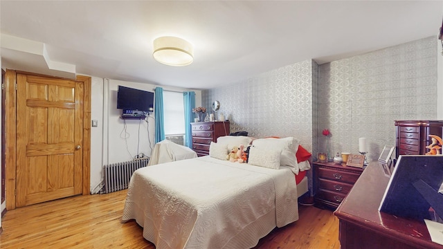 bedroom with radiator heating unit and wood-type flooring