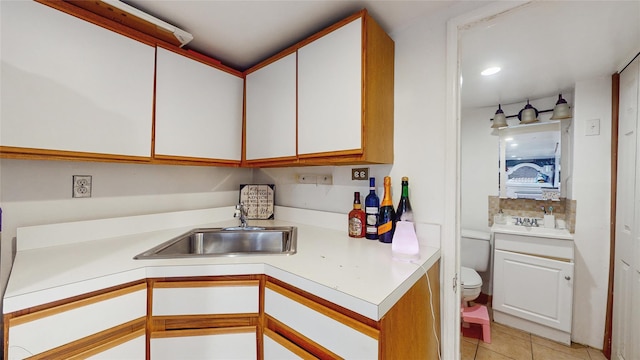 kitchen featuring light tile patterned flooring, white cabinetry, and sink