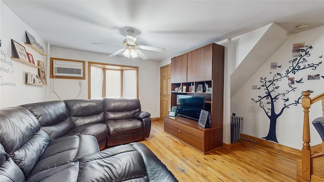 living room featuring a wall mounted AC, ceiling fan, and light hardwood / wood-style floors