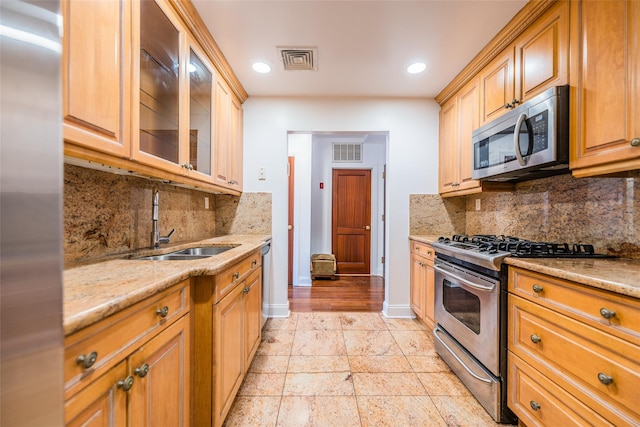 kitchen featuring light stone countertops, sink, appliances with stainless steel finishes, and tasteful backsplash