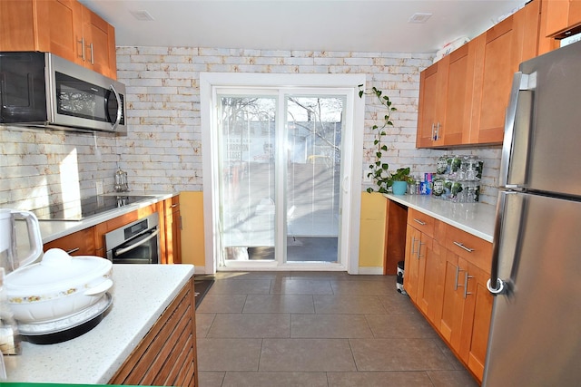 kitchen with light stone countertops, stainless steel appliances, and dark tile patterned floors