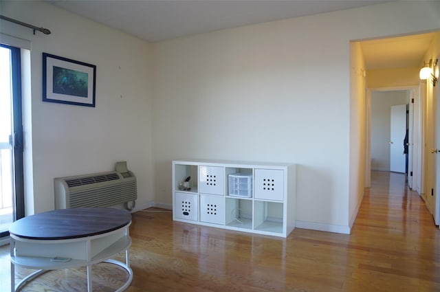 sitting room featuring a wall mounted air conditioner and light hardwood / wood-style floors