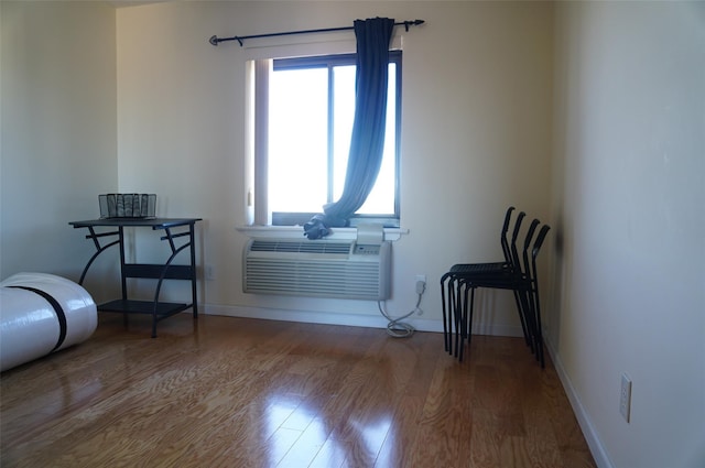 sitting room with a wall mounted air conditioner and wood-type flooring