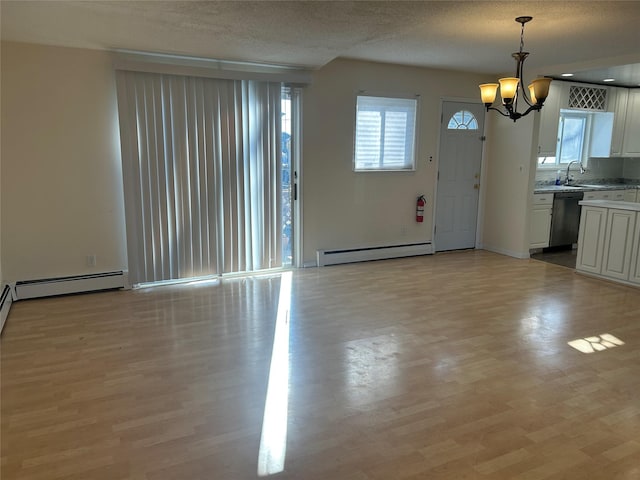 interior space with a baseboard radiator, an inviting chandelier, light hardwood / wood-style floors, and sink