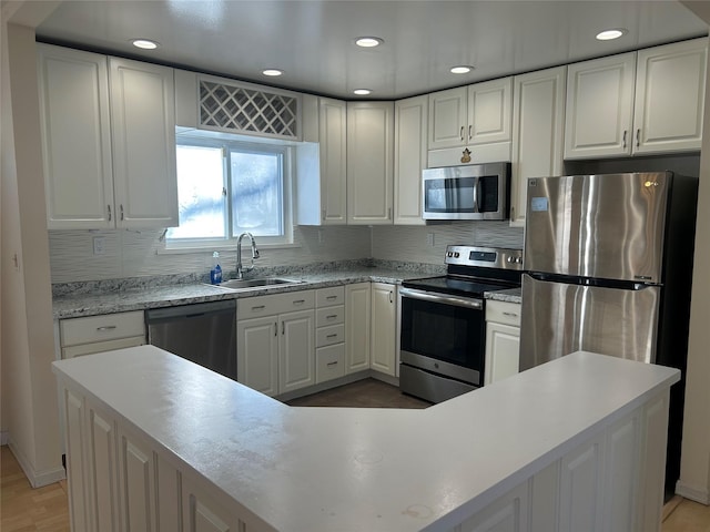 kitchen with appliances with stainless steel finishes, tasteful backsplash, white cabinetry, and sink