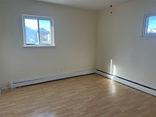 unfurnished room featuring light wood-type flooring, a baseboard radiator, and a healthy amount of sunlight