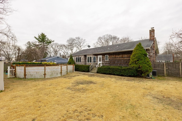 back of property with central AC unit and a lawn