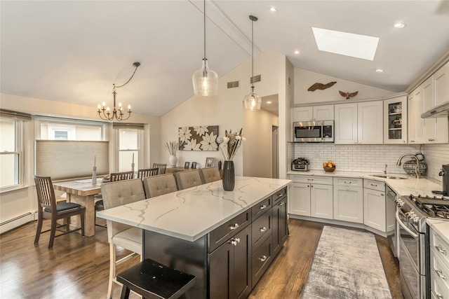 kitchen with decorative backsplash, a skylight, stainless steel appliances, decorative light fixtures, and a center island