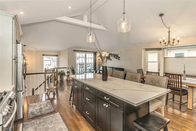 kitchen with decorative light fixtures, a kitchen island, a breakfast bar area, and lofted ceiling with beams