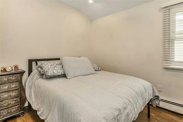 bedroom featuring wood-type flooring, baseboard heating, and lofted ceiling