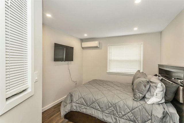 bedroom featuring dark hardwood / wood-style flooring and a wall unit AC