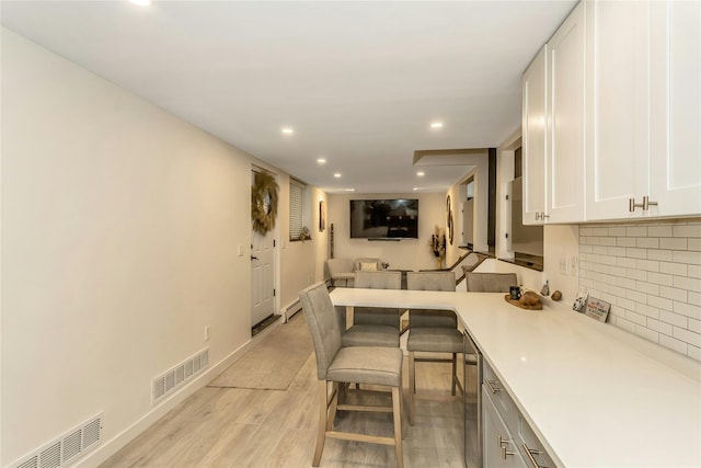 kitchen featuring a breakfast bar, white cabinetry, and light hardwood / wood-style flooring