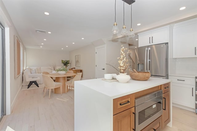 kitchen featuring white cabinetry, a center island, stainless steel appliances, pendant lighting, and decorative backsplash