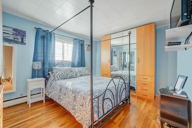 bedroom with hardwood / wood-style flooring and a baseboard heating unit