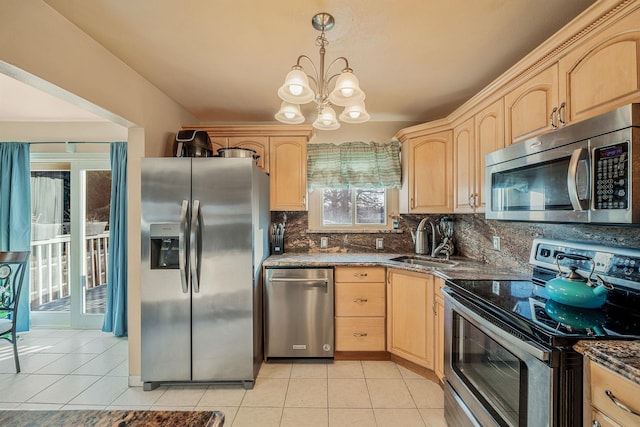 kitchen featuring pendant lighting, appliances with stainless steel finishes, dark stone counters, light brown cabinetry, and sink