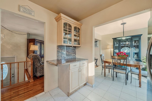 kitchen with tasteful backsplash, dark stone countertops, a wall mounted air conditioner, hanging light fixtures, and light tile patterned floors