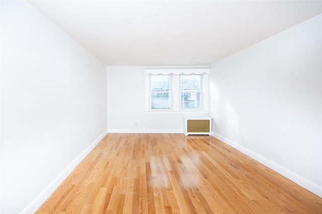 spare room featuring radiator heating unit and light hardwood / wood-style flooring