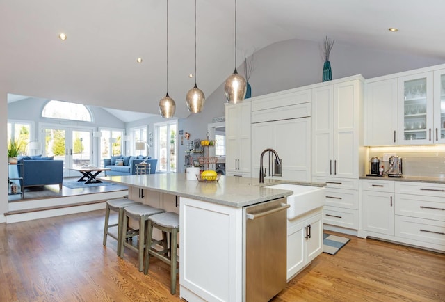 kitchen with french doors, sink, white cabinetry, dishwasher, and an island with sink