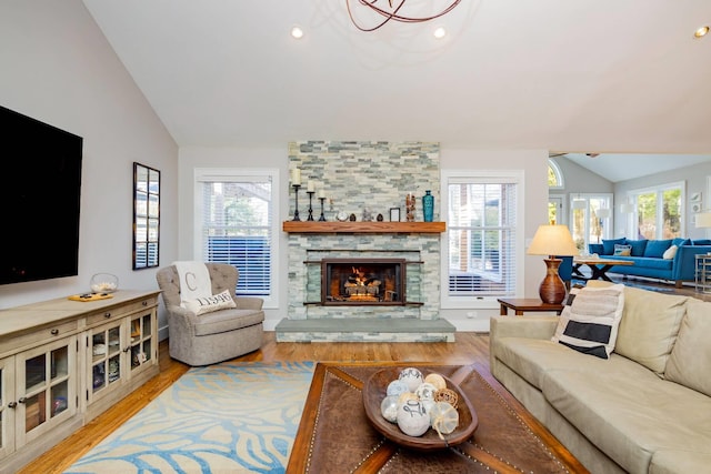 living room with lofted ceiling, hardwood / wood-style floors, and a stone fireplace