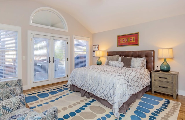 bedroom with vaulted ceiling, access to exterior, and light wood-type flooring