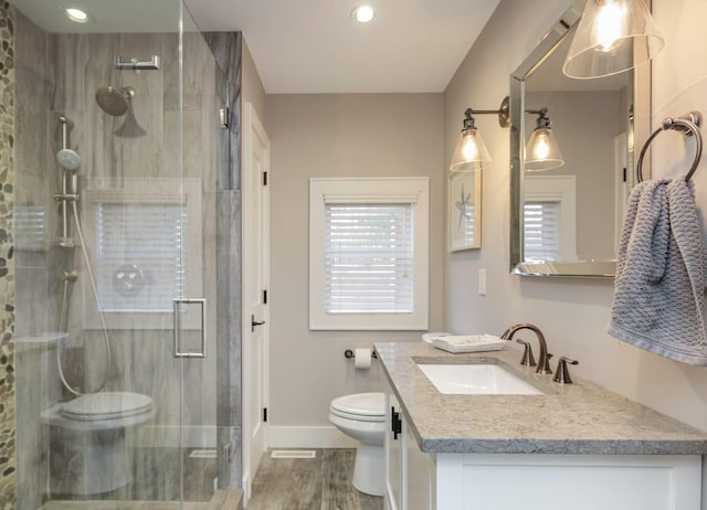 bathroom with a shower with door, vanity, hardwood / wood-style flooring, and toilet