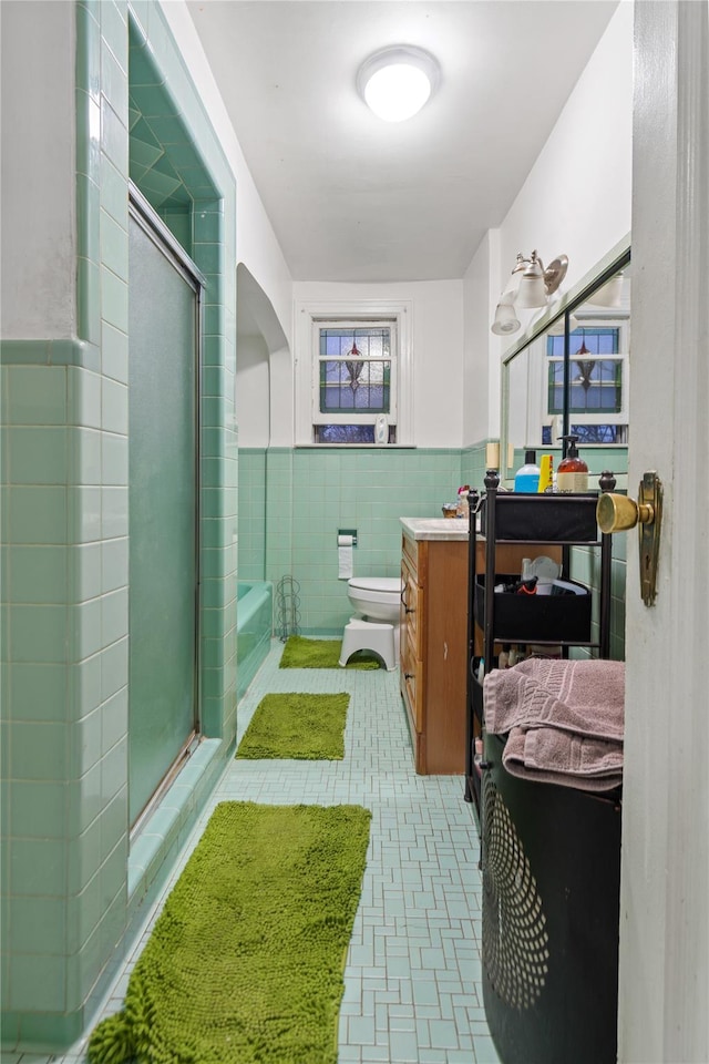 full bathroom featuring vanity, toilet, tile walls, and separate shower and tub