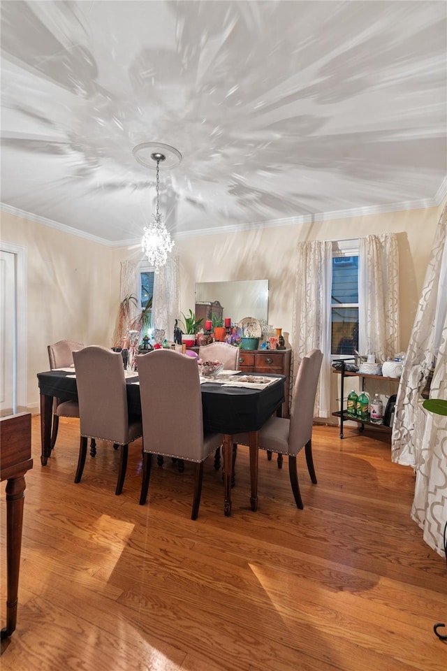 dining space with light wood-type flooring, ornamental molding, and a chandelier