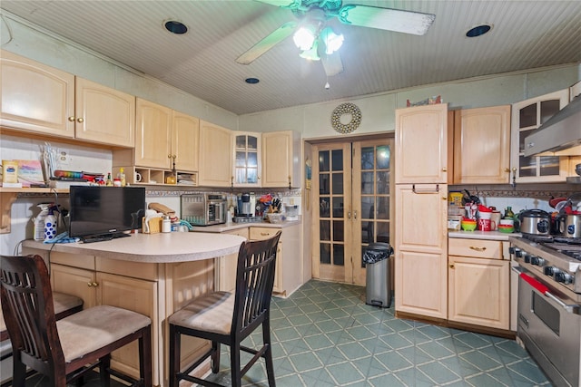 kitchen with a breakfast bar, light brown cabinetry, and stainless steel stove