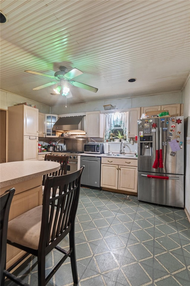 kitchen featuring high quality appliances, light brown cabinetry, wall chimney exhaust hood, and sink