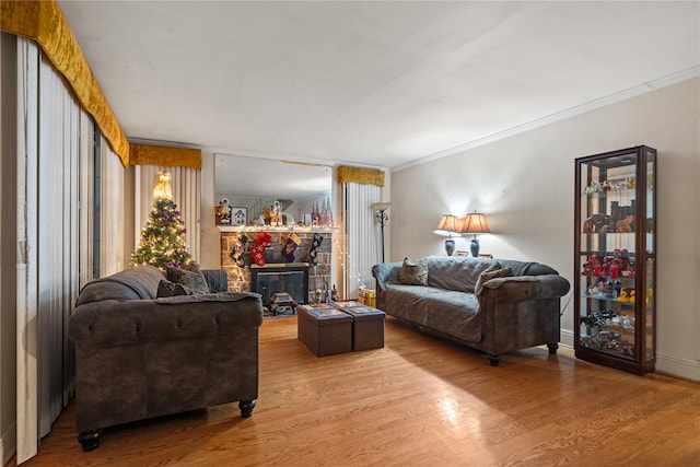 living room with hardwood / wood-style flooring, a stone fireplace, and ornamental molding