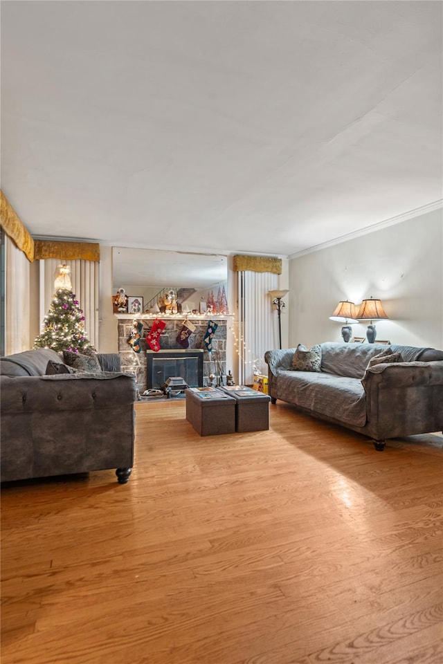 bedroom with a stone fireplace, light hardwood / wood-style flooring, and ornamental molding