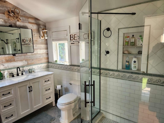 bathroom with vanity, lofted ceiling, toilet, tile walls, and a shower with shower door