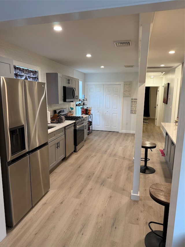 kitchen featuring gray cabinetry, decorative backsplash, light hardwood / wood-style flooring, and stainless steel appliances