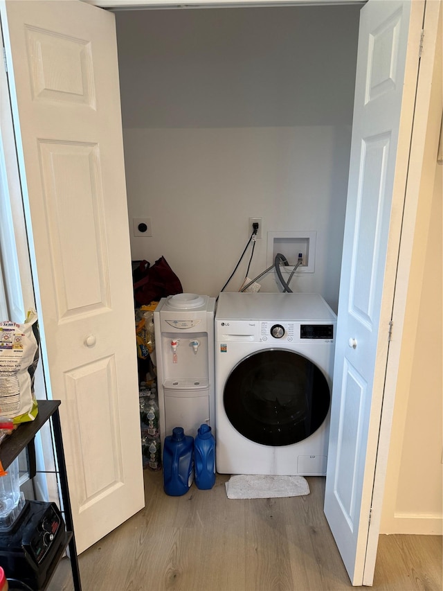 clothes washing area with washer / dryer and light hardwood / wood-style floors