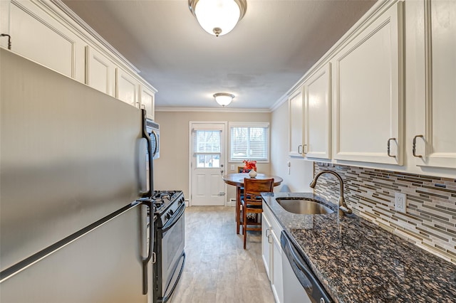 kitchen with white cabinetry, stainless steel appliances, dark stone counters, crown molding, and sink