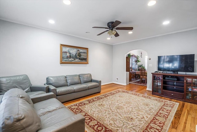 living room featuring hardwood / wood-style flooring, ornamental molding, and ceiling fan