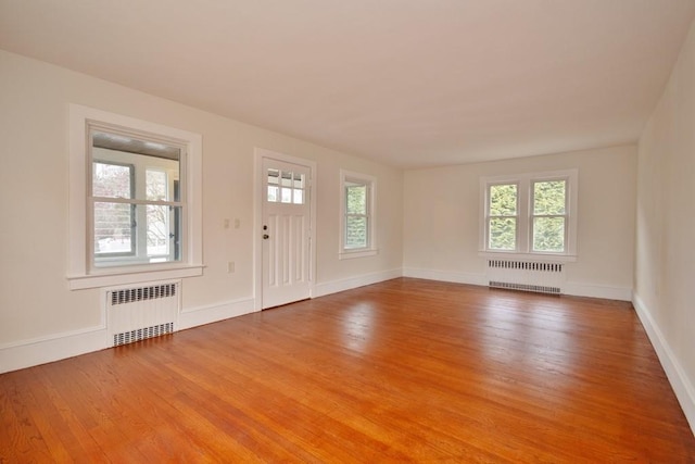 entrance foyer featuring a healthy amount of sunlight, radiator heating unit, and light hardwood / wood-style flooring