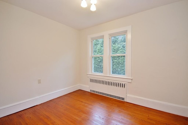 spare room with hardwood / wood-style flooring and radiator heating unit